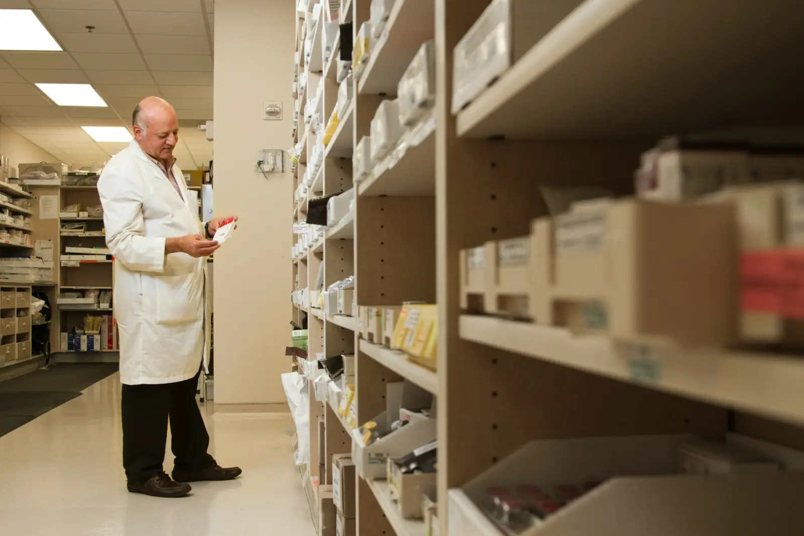 Un farmacista controlla una confezione tra gli scaffali del magazzino